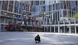  ?? NG HAN GUAN — THE ASSOCIATED PRESS ?? A man wearing a mask squats in front of an empty mall area on Monday in Beijing.