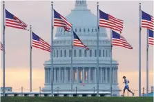  ?? J. DAVID AKE/ASSOCIATED PRESS ?? A runner passes flags at the base of the Washington Monument, with the U.S. Capitol dome in the background, early one morning in September.