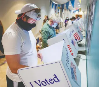  ?? MICHAEL CIAGLO/ GETTY IMAGES ?? A voter casts his in-person absentee ballot in Charleston, South Carolina on Friday. Voting rules in the American election now underway are determined by each state and vary greatly.