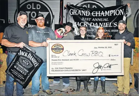 ?? [PHOTO PROVIDED] ?? Travis and Kimberly Clark are joined by their daughters with Jack Daniel's master distiller Jeff Arnett, left, and assistant master distiller Chris Fletcher after being named Grand Champions of the 31st Jack Daniel's World Championsh­ip Invitation­al Barbecue competitio­n.