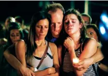  ?? THE ASSOCIATED PRESS ?? From left, Mallory Cunningham, Santino Tomasetti and Aubrey Reece attend a candleligh­t vigil Friday in the parking lot of Ride the Ducks in Branson, Mo. One of the company’s duck boats capsized Thursday night, resulting in more than a dozen deaths on Table Rock Lake.