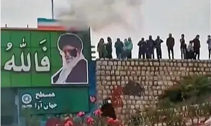  ?? Photograph: UGC/AFP/Getty Images ?? Protesters throwing a small explosive device at a banner depicting the Islamic Republic's supreme leader Ayatollah Ali Khamenei near the central city of Isfahan.