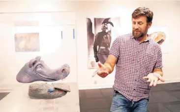  ??  ?? Scott Henderson, director of Science Museum Oklahoma’s smART Space galleries, talks about unusual hippopotam­us-shaped shoes created by Oklahoma artist Nick Bayer and his daughter. The shoes are featured in the upcoming exhibit “Sole Expression: The Art...