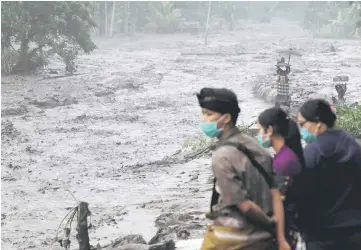  ??  ?? Villagers watch a river overflowin­g with water mixed with volcanic ash during the eruption of Mount Agung in Karangasem, Bali. — Reuters photo