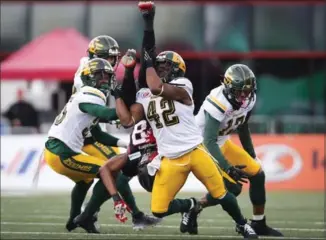  ?? JEFF MCINTOSH, THE CANADIAN PRESS ?? Edmonton Eskimos’ Cauchy Muamba, centre right, upends Stampeders’ Kamar Jorden in the first quarter in the CFL’s West final Sunday. The Stamps, however, upended Edmonton on the scoreboard, 32-28.