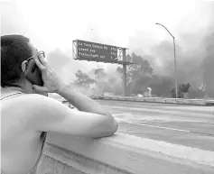  ??  ?? A man watches as thick smoke and flames burn near the community of Tujunga during the La Tuna Fire near Burbank. — AFP photo