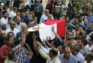  ?? ALAA ELKASSAS — THE ASSOCIATED PRESS ?? People carry the coffin, covered with the an Egyptian flag, of police captain Ahmed Fayez who was killed in a gun battle in al-Wahat al-Bahriya area in Giza province, about 135 kilometers (84 miles) southwest of Cairo, during his funeral at Al-Hosary...