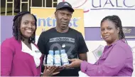  ??  ?? Livingston Scott/Gleaner Writer Danielle Wright (left), dietitian and brand ambassador for Intrust Nutrition Shake, is all smiles as she presents a case of the beverage to Kingston College head coach Ludlow Bernard (centre), while vice-principal Marguerita Douglas looks on on Wednesday, August 8, 2018. The presentati­on was made at the school’s campus on North Street, Kingston.