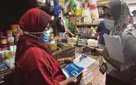  ?? PIC BY MOHD ADAM ARININ ?? A healthcare worker distributi­ng flyers on Covid-19 vaccinatio­n in Kota Kinabalu yesterday.