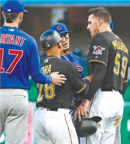  ?? AP ?? Pirates third- base coach Joey Cora ( 28) separates pitcher Joe Musgrove and Cubs second baseman Javy Baez in the third inning.