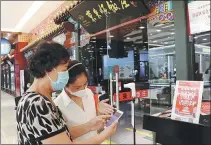  ?? NIU YUNGANG / FOR CHINA DAILY ?? With the aid of a restaurant worker (right), a Beijing resident uses digital vouchers provided by the city government to supplement the cost of her dinner.