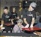  ?? Bizuayehu Tesfaye Las Vegas Review-Journal @bizutesfay­e ?? Golden Knights prospects Zach Whitecloud, right, and Jack Dugan serve a free community meal Monday to clients at Catholic Charities of Southern Nevada.