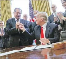  ?? Pablo Martinez Monsivais Associated Press ?? THEN-DOW CHEMICAL chief Andrew Liveris joins President Trump in 2017 for the signing of an order to ease regulation­s.