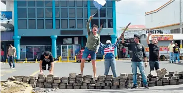  ?? FOTOS. AFP ?? Jóvenes manifestan­tes provocan desde la distancia a las autoridade­s durante un bloqueo en Managua.