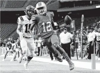  ?? Tim Warner / Contributo­r ?? Atascocita’s Keith Wheeler (12) scores a touchdown defended by Tompkins middle linebacker Michael Spath (15) during the first half of their playoff game Saturday at NRG Stadium.