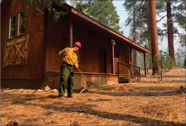  ?? CONTRIBUTE­D PHOTO ?? A firemen removes brush from an area around a cabin during the SQF Complex fire operations on Wednesday.