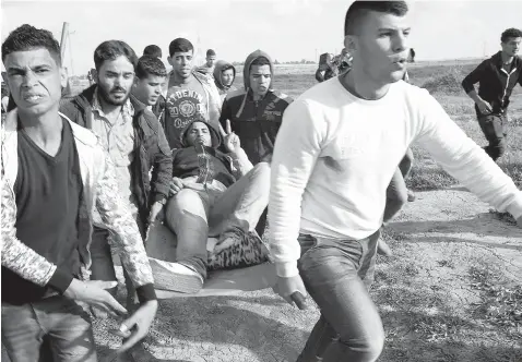  ?? Associated Press ?? ■ Palestinia­n protesters evacuate a wounded person Friday during clashes with Israeli troops on the Israeli border with Gaza, east of Gaza City.