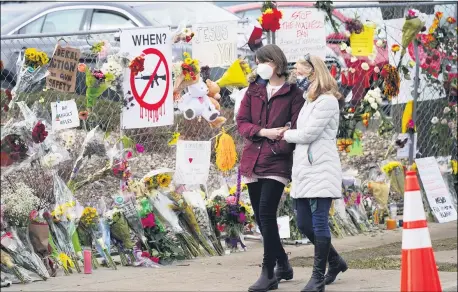  ?? DAVID ZALUBOWSKI — THE ASSOCIATED PRESS ?? Mourners walk along the temporary fence put up around the parking lot of a King Soopers grocery store where a mass shooting took place earlier in the week Thursday, March 25, in Boulder, Colo.