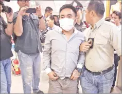  ??  ?? Boonchai (centre) is escorted past journalist­s as he is processed at a police station in Bangkok.— AFP photo
