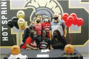  ?? The Sentinel-Record/James Leigh ?? ■ Hot Springs’ Jaylia Reed, seated center, smiles after signing a letter of intent to play basketball at Arkansas State University Mid-South during a ceremony at Trojan Arena Friday. Reed was joined by, seated from left, sister Anaya Reed, mother Jeremy Burns, standing from left, Lady Trojans assistant coach Nicole Lowe, friend Jurnee Hicks, brother Leshawn Reed and Lady Trojans head coach Josh Smith.