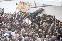  ?? REUTERS ?? PALESTINIA­NS gather to receive aid outside a warehouse as Gaza residents face crisis levels of hunger, amid the ongoing conflict between Israel and Hamas, in Gaza City, March 18.