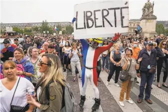  ?? Michel Euler / Associated Press ?? An antivaccin­e demonstrat­or dressed in the colors of the French flag joins a rally in Paris. More than 100,000 people protested across France against the government’s latest restrictio­ns.