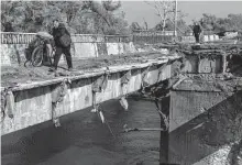  ?? Paula Bronstein/Getty Images ?? Refugees flee over a destroyed bridge on Saturday in Kupiansk, Ukraine. The city has been successful­ly captured by Ukrainian Armed Forces pushing back the Russians.