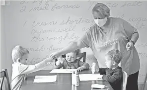  ??  ?? Leitermann sets up an artwork project for Ethan, left, Burke and Henry at Impression­s Family Child Care.