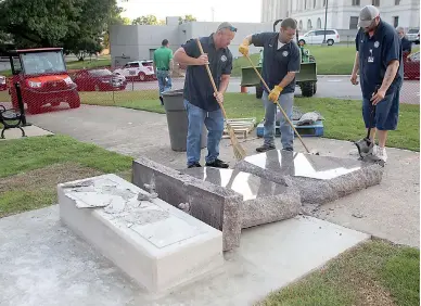  ?? Special to the Arkansas Democrat-Gazette ?? State Department staff members pick up pieces of the newly installed Ten Commandmen­ts monument Wednesday on the Arkansas Capitol grounds after it was toppled by a man driving a car before dawn in Little Rock.