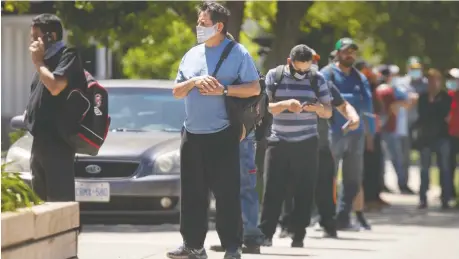  ?? DAX MELMER ?? Migrant workers wait outside the Canadian Imperial Bank of Commerce on Erie Street South in Leamington recently. The Mexican government has put a pause on sending migrant workers to Canada due to COVID-19 concerns.