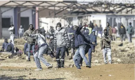  ?? (Photo: AFP) ?? Disgruntle­d residents throw rocks as they confront police officers at the entrance of a partially looted mall in Vosloorus, on July 13, 2021.