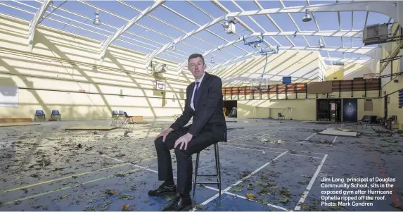  ??  ?? Jim Long, principal of Douglas Community School, sits in the exposed gym after Hurricane Ophelia ripped off the roof. Photo: Mark Condren