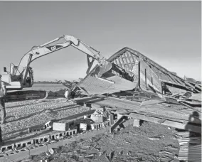  ?? ?? A trackhoe operator pushes the collapsed top of a barn on the Nowakowski­s’ land near Dale off its old foundation.