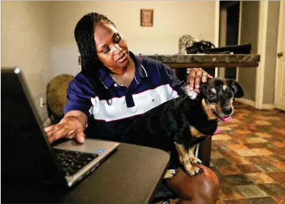  ?? CURTIS COMPTON / CCOMPTON@AJC.COM ?? Monica Griffin teleworks from her apartment with her dog, Prince, in Stonecrest. She’s thankful she has a landlord who did not file for eviction and allowed her to pay back rent when she finally received her unemployme­nt benefits in June.