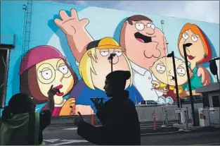 ??  ?? DENERING and Katranis painted the “Family Guy” mural as a salute to creator Seth MacFarlane. Denering’s four-decade career includes creating backdrops for more than 200 films.