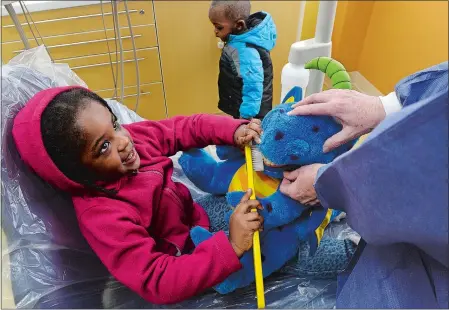  ?? DANA JENSEN/THE DAY ?? Before having her own teeth cleaned by dental hygienist Patricia McCay on Wednesday, Judelyne Lorcy, 2, of New London brushes the teeth of a stuffed dinosaur while her brother, Jermiah Lorcy, 1, wanders around the exam room at the Community Health Care...