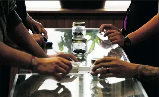  ?? — THE ASSOCIATED PRESS FILES ?? Customers and clerks at Top Shelf Cannabis in Bellingham, Wash., pass ‘sniff jars’ back and forth on a glass countertop on July 8, 2014, the first day that marijuana sales were legal in Washington state.