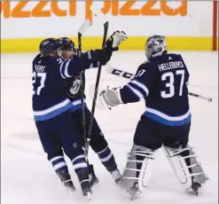  ?? The Canadian Press ?? Winnipeg Jets forwards Nikolaj Ehlers (27) and Mark Scheifele rush to goaltender Connor Hellebuyck (37) after he made the game-winning save against the Nashville Predators during the shootout on Sunday in Winnipeg.