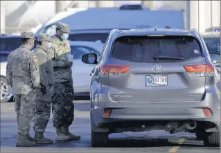  ?? PHOTOS BY MICHAEL GARD/POST-TRIBUNE ?? Members of the Indiana National Guard speak with a resident awaiting their turn to get the COVID-19 vaccine at Ivy Tech Community College in East Chicago on Friday.