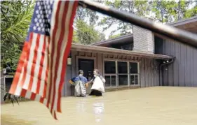  ?? THE ASSOCIATED PRESS ?? Gaston Kirby, right, and Juan Minutella leave Kirby’s flooded home Monday in the aftermath of Hurricane Harvey near the Addicks and Barker Reservoirs, in Houston.