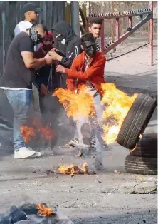  ?? AFP ?? Palestinia­n protesters burn tires on Sunday amid clashes with Israeli security forces in the city center of Hebron in the occupied West Bank.