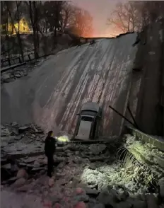  ?? Courtesy of the Pittsburgh Public Safety Department ?? Pittsburgh Police Officer Tyler Nestler peers into the ravine where the Fern Hollow Bridge collapsed Jan. 28. Officer Nestler was making an initial search for people whose vehicles were on the bridge.