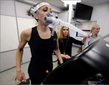  ??  ?? In this April 23 photo, research scientist Leila Walker (left) is assisted by nutritiona­l physiologi­st Holly McClung (center) as they demonstrat­e equipment designed to evaluate fitness levels in female soldiers, not shown, who have joined elite fighting units such the Navy Seals, at the U.S. Army Research Institute of Environmen­tal Medicine, at the U.S. Army Combat Capabiliti­es Developmen­t Command Soldier Center, in Natick, Mass. AP PHOTO/STEVEN SENNE