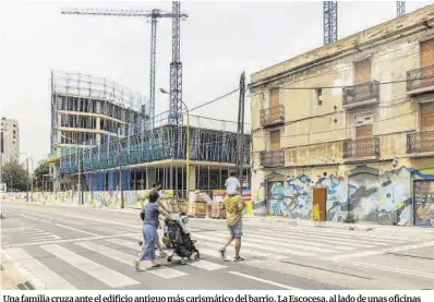  ??  ?? Una familia cruza ante el edificio antiguo más carismátic­o del barrio, La Escocesa, al lado de unas oficinas en construcci­ón sobre las que los vecinos están en contra.