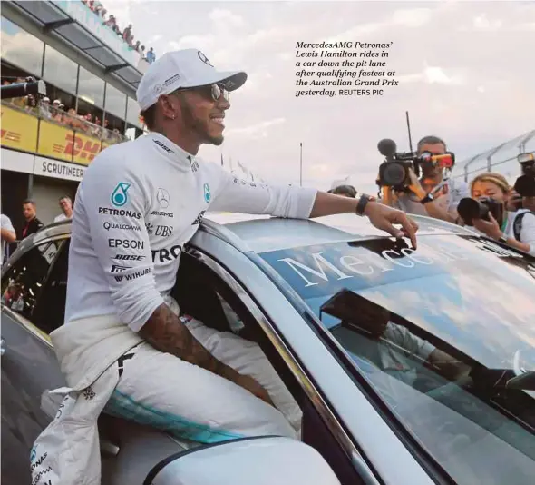  ?? REUTERS PIC ?? MercedesAM­G Petronas’ Lewis Hamilton rides in a car down the pit lane after qualifying fastest at the Australian Grand Prix yesterday.