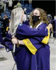  ?? STAFF PHOTO BY TROY STOLT ?? Madison Tino and Arrie Beth Hyder embrace after graduating with the UTC class of 2021 at McKenzie Arena on Friday.