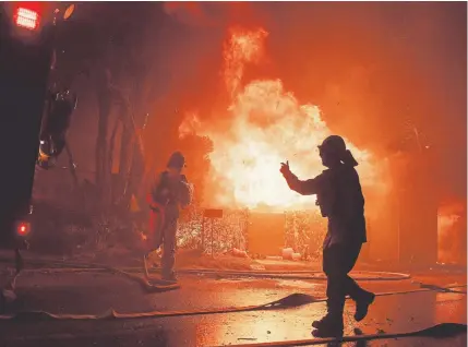  ?? Christian Monterrosa, The Associated Press ?? Firefighte­rs try to save a home on Tigertail Road during the Getty fire Monday in Los Angeles.