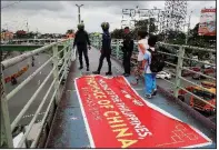  ?? AP/BULLIT MARQUEZ ?? People step around a banner Thursday that’s critical of Philippine­s President Rodrigo Duterte’s policy toward China and territoria­l waters. The banner reads “Welcome to the Philippine­s, Province of China.”