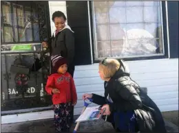  ?? The Associated Press ?? CANVASSING NEIGHBORHO­ODS: Doug Jones campaign volunteer Dana Ellis, right, talks to Ebonique Jiles, top left, and her son, on Saturday in Birmingham, Ala., about voting in Tuesday’s senatorial election. The Jones campaign is targeting African-Americans...