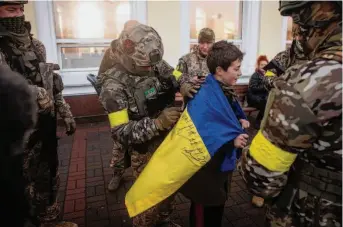  ?? Chris McGrath/Getty Images ?? A boy has his Ukraine national flag signed by soldiers as he waits on a rail platform in Kherson for the first train to arrive since the city recently was liberated from Russian occupation.